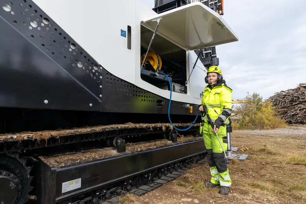 An operator beside an open service compartment on the rig.