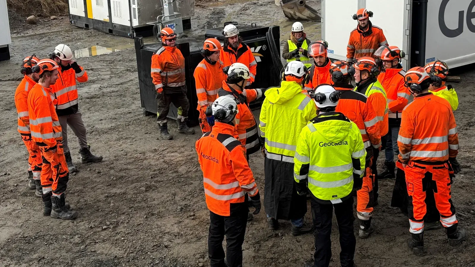 Geocadia field crew gathered for a team briefing beside site equipment